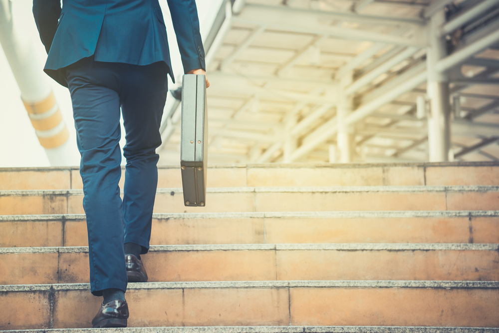 Man holding a briefcase walking up the steps