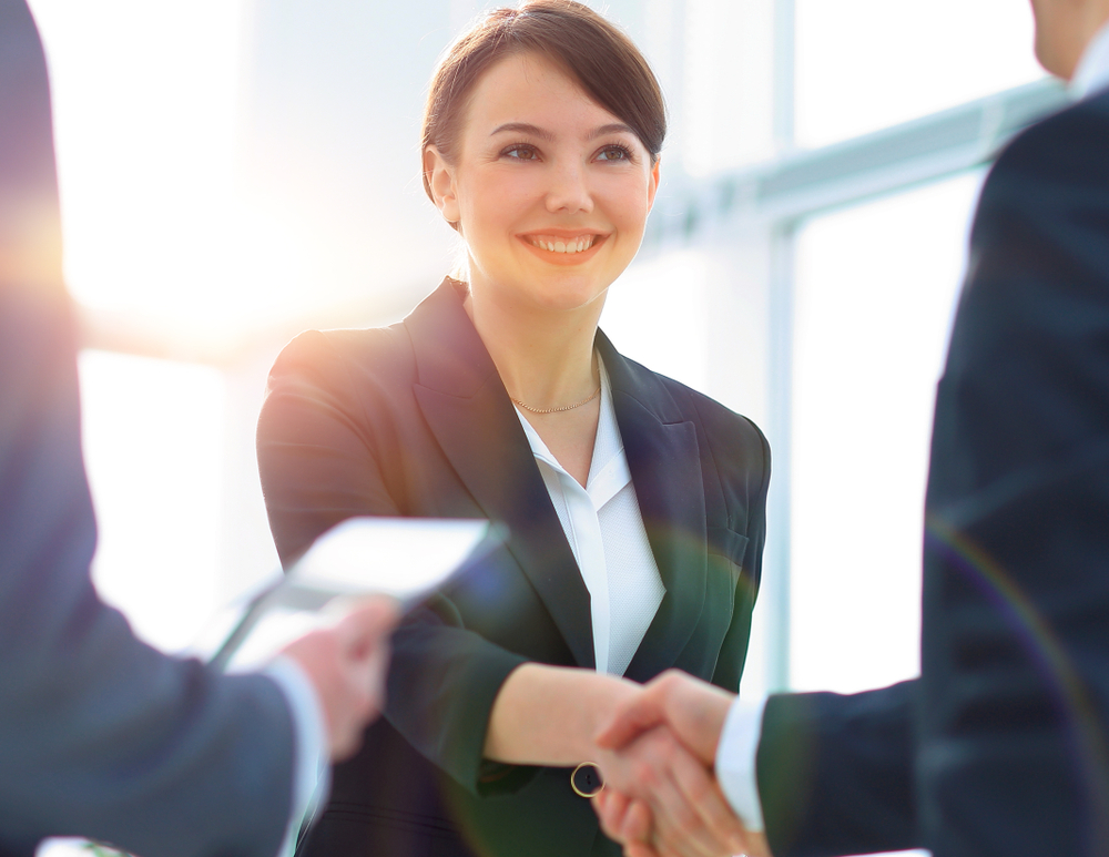 Woman smiling as she shakes hands with someone